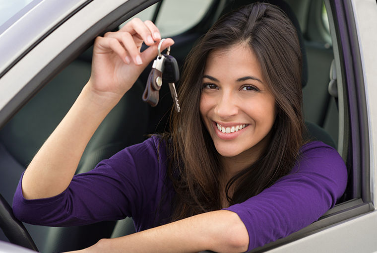 Žena sjedi u automobilu i drži ključeve nakon prve registracije
