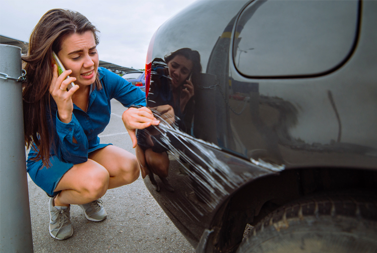 Žena koja je imala sudar priča na telefon i provjerava štetu na svoj automobilu