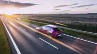 Ljubičasti auto vozi po cesti.